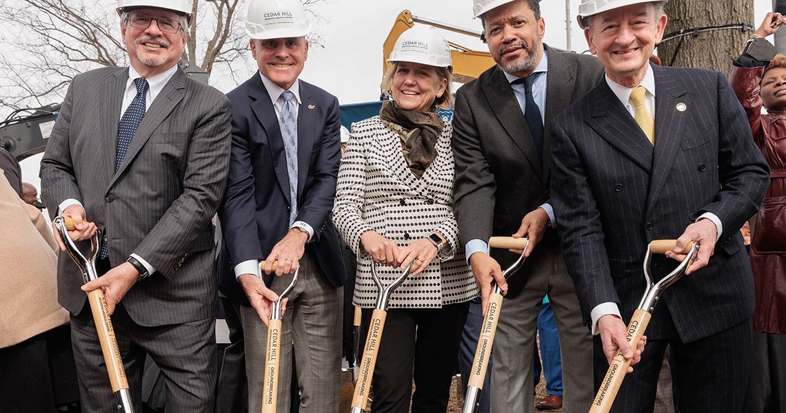 Five people are holding shovels at a ground-breaking ceremony