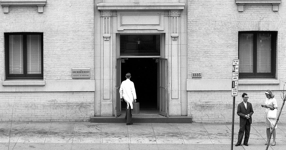 A medical student standing before the H. Street Medical School entrance at GW