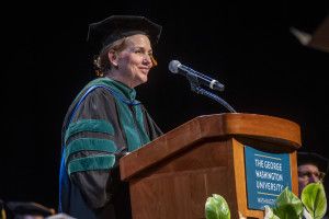 Bass speaking at podium wearing regalia