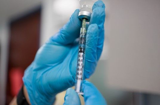 Close-up for gloved hands holding a syringe needle